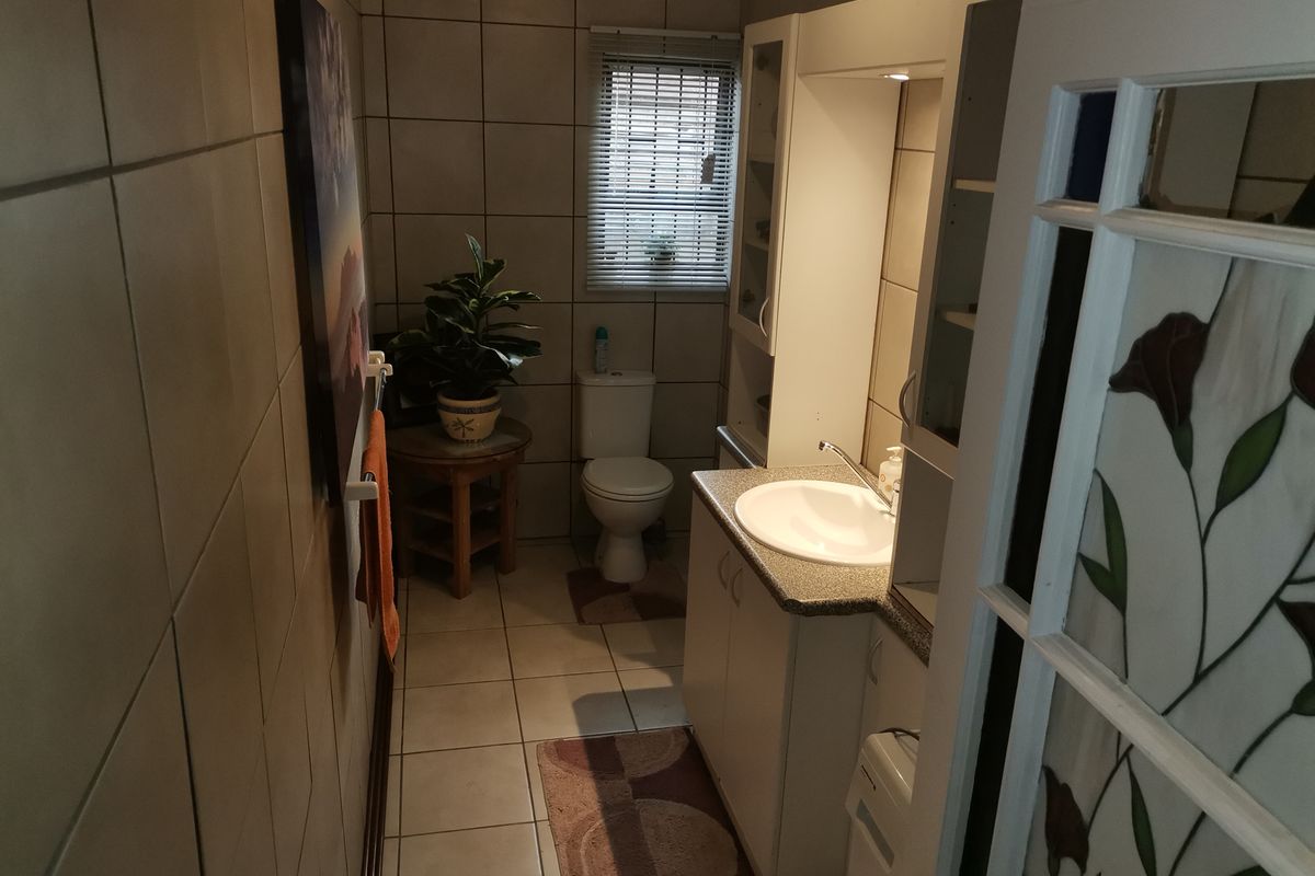 A functional bathroom featuring tiled walls and flooring, a vanity unit with an integrated sink, a toilet, and a decorative stained glass door.