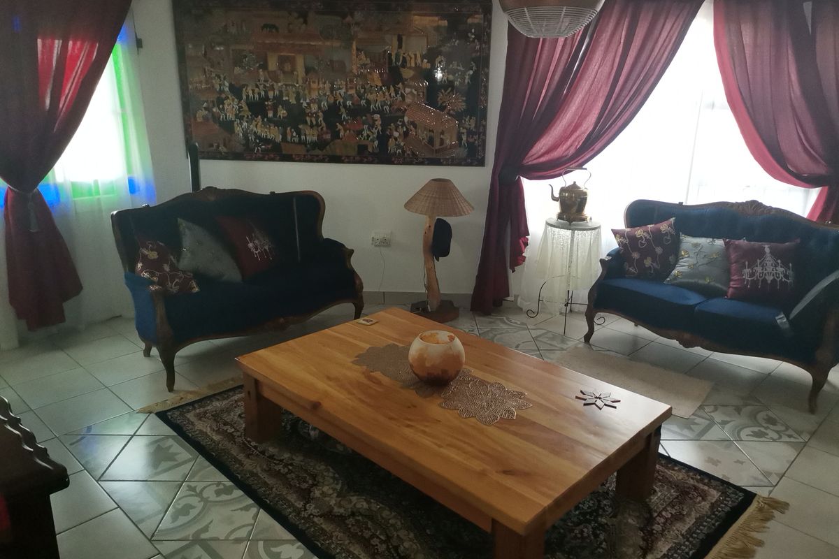 A living room featuring tiled flooring with decorative accents and large windows dressed with curtains.