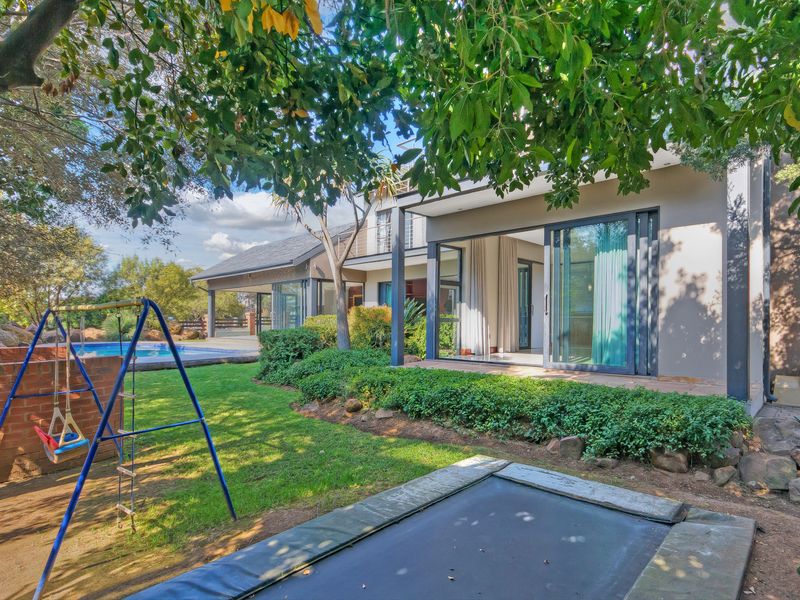 Rear view of the property featuring a landscaped garden, swimming pool, and a covered patio with large sliding glass doors for indoor-outdoor flow.
