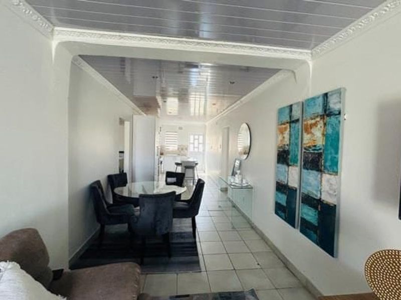 Open plan living and dining area featuring tiled flooring and glossy ceiling panels with decorative cornice detailing.