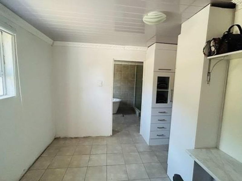 A vacant bedroom featuring built-in cabinetry, tiled flooring, and direct access to an en-suite bathroom area.