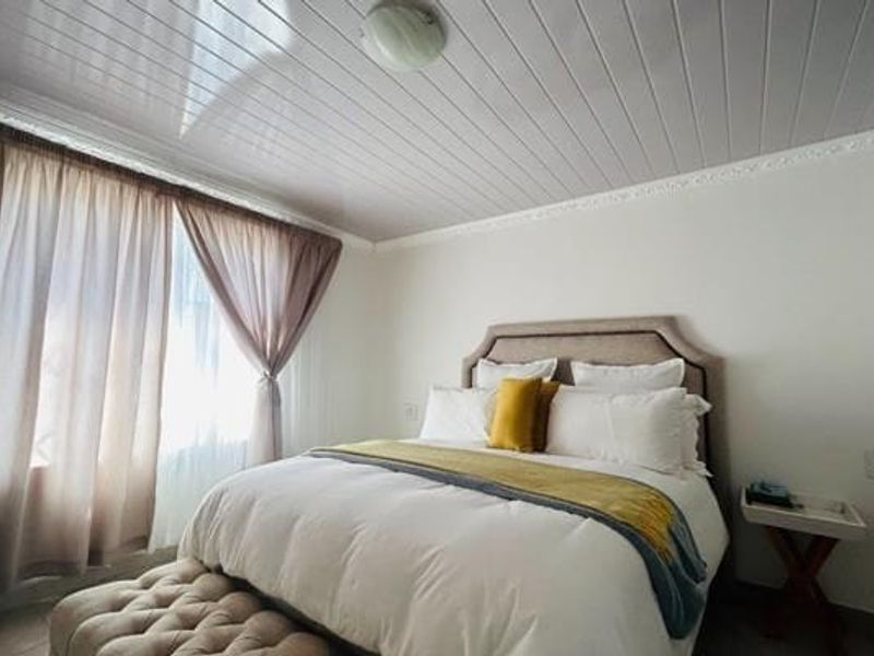 A well-lit bedroom featuring a tongue and groove ceiling with decorative coving and neutral wall finishes.