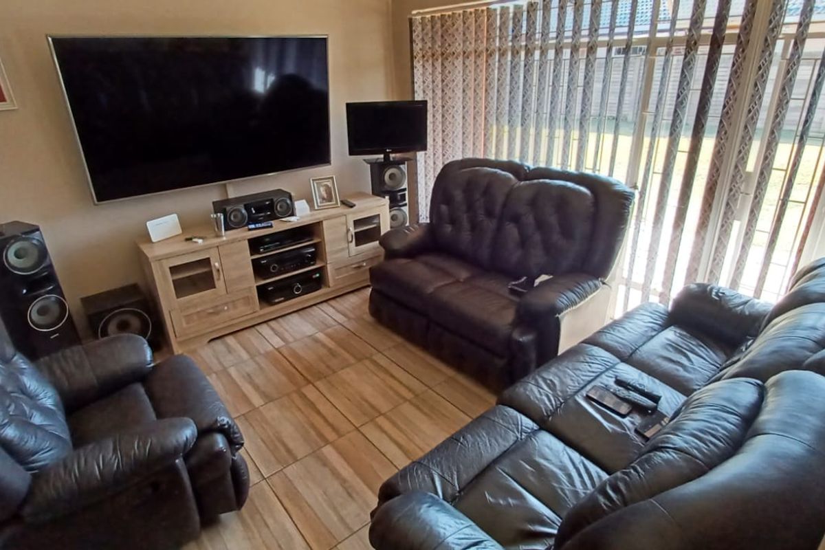 A comfortable living room featuring tiled flooring and large sliding glass doors that provide access to the outdoor area.