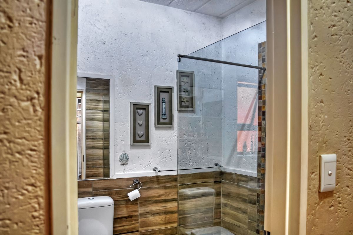 A modern bathroom featuring a glass shower screen, wood-look wall tiling, and a textured wall finish.