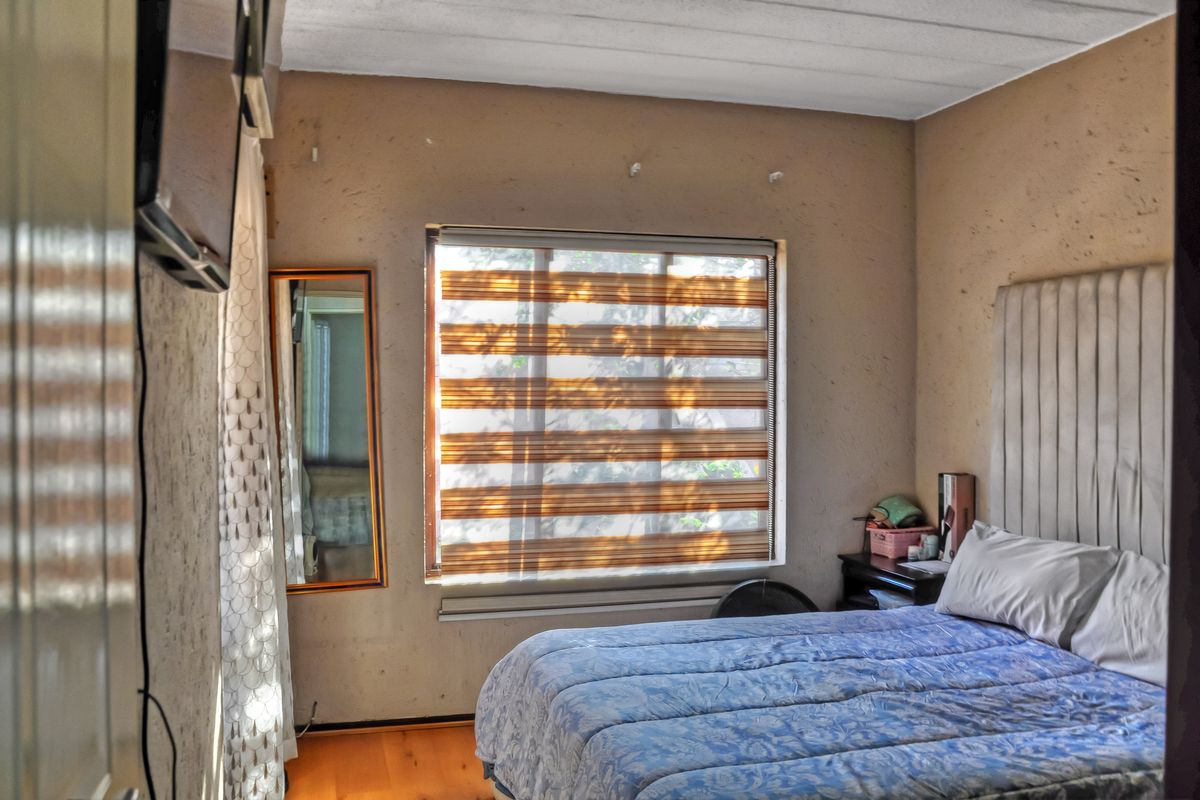 A bedroom featuring textured walls, laminate flooring, and modern zebra blinds, offering a functional space with potential for cosmetic updates.