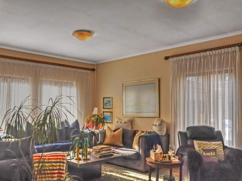 A living room featuring natural light through large windows with curtain rods and flush-mount ceiling lighting.