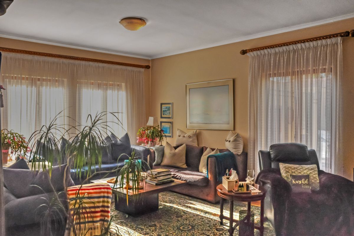 A comfortable living room featuring large windows with curtain rods and natural light, providing a warm and inviting atmosphere.