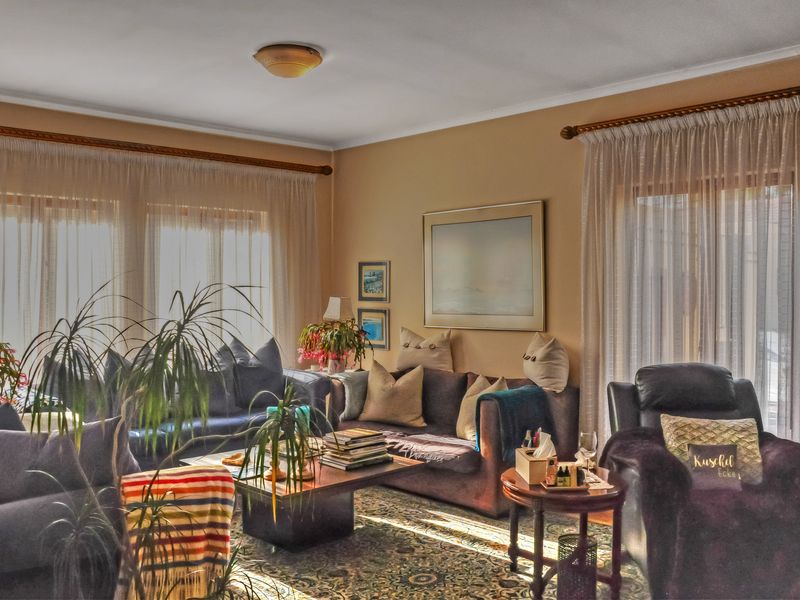 A comfortable living room featuring large windows with curtain rods and natural light, providing a warm and inviting atmosphere.