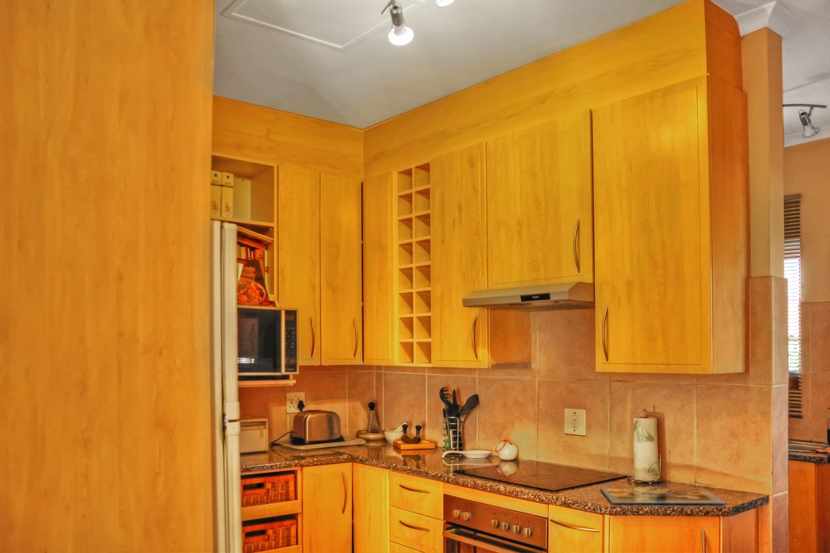 A functional kitchen featuring light wood-toned cabinetry, granite-look laminate countertops, a built-in oven, electric cooktop, and a tiled backsplash.