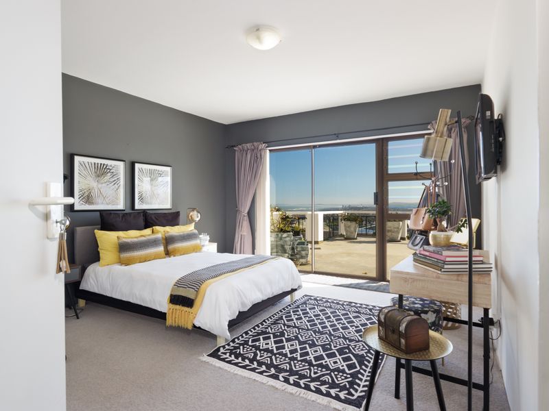 Spacious bedroom featuring an accent wall, carpeted flooring, and large sliding glass doors that open onto a private balcony with scenic views.