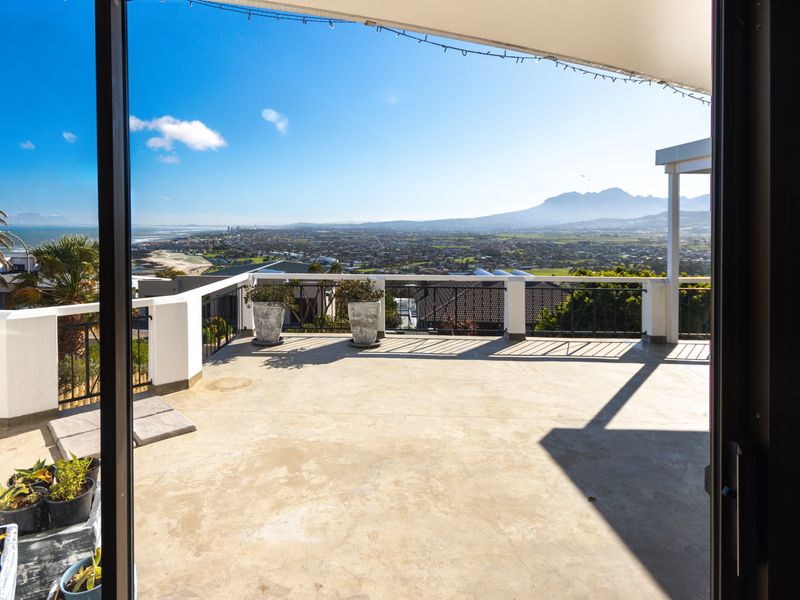 Spacious open-air balcony featuring a concrete floor and metal balustrade, offering expansive panoramic views of the surrounding landscape and mountains.