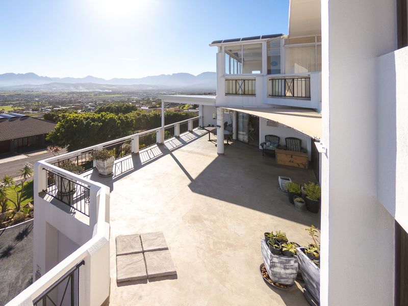 Spacious elevated balcony featuring concrete flooring, metal railings, and a retractable awning, offering expansive panoramic views of the surrounding landscape.