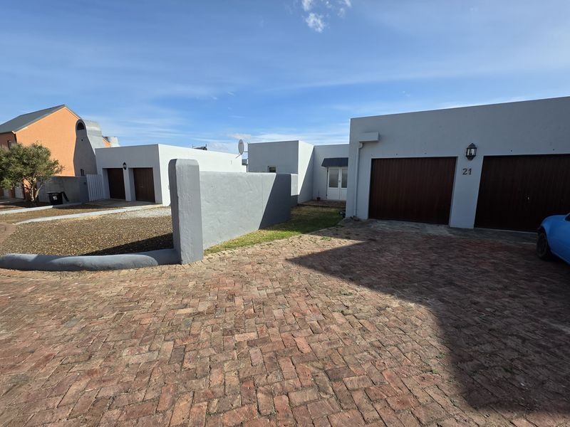 Front exterior view of the property featuring a brick paved driveway, double garage, and boundary wall.
