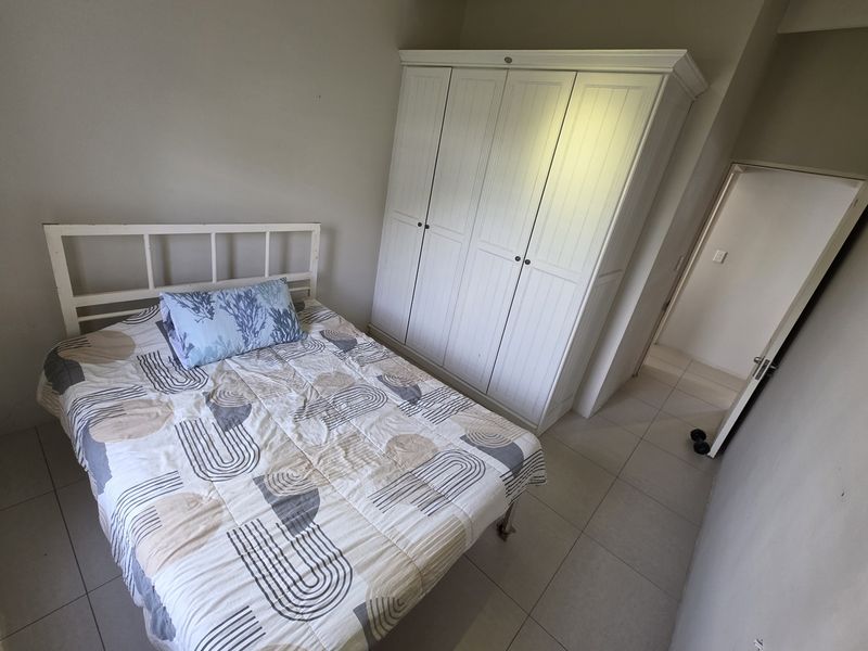 A bedroom featuring tiled flooring and a built-in wardrobe, offering a functional space with neutral wall finishes.