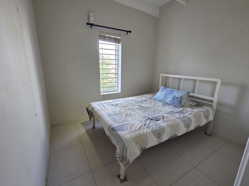 A simple bedroom featuring tiled flooring and a single window with a curtain rod, offering a neutral space ready for personalization.
