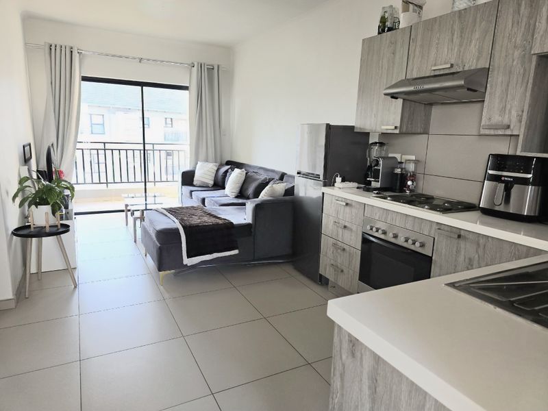 Modern open-plan living area featuring a contemporary kitchen with built-in appliances and seamless access to a private balcony through sliding glass doors.