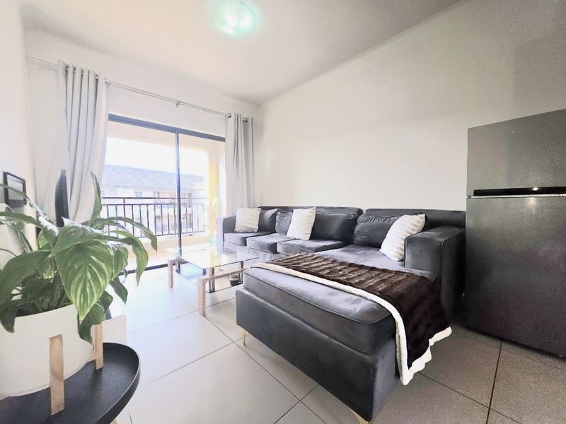 Open plan living area featuring neutral tiled flooring and a sliding glass door providing access to a private balcony.