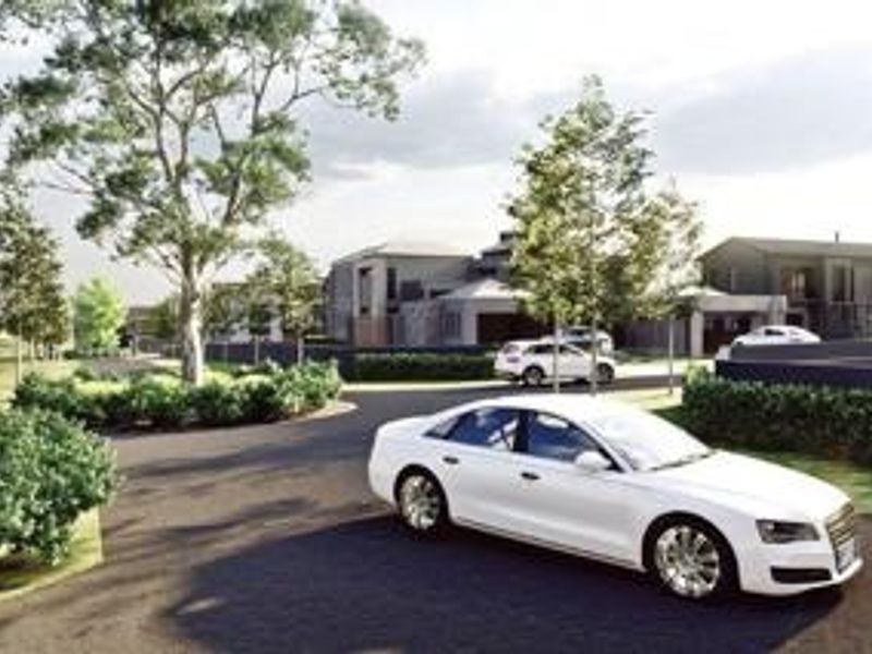 A perspective view of a residential estate entrance featuring paved roads, landscaped greenery, and modern architectural building designs.