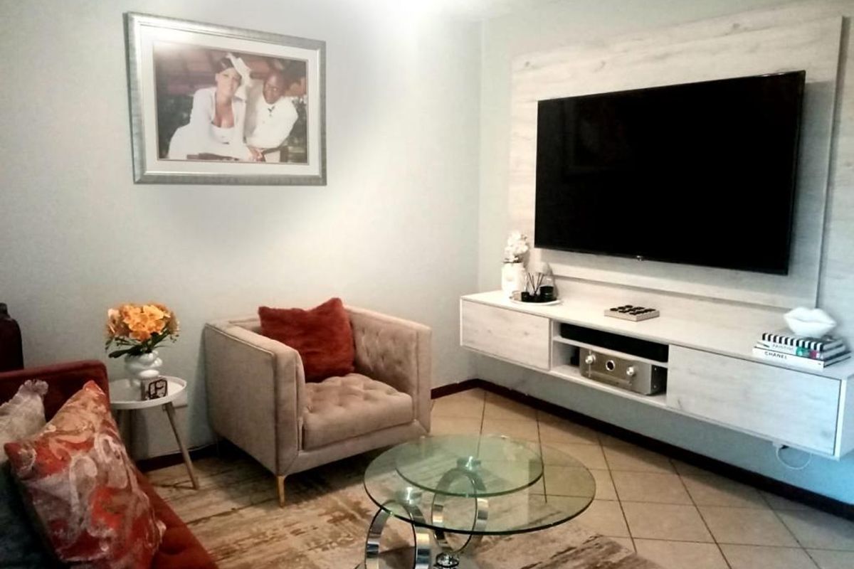 A cozy living room featuring a wall-mounted media console and tiled flooring, providing a functional and well-maintained space for relaxation.