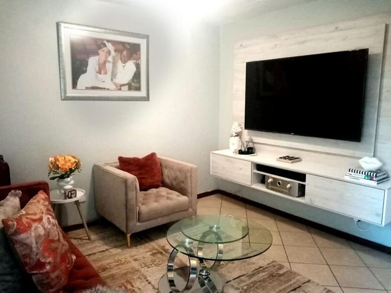 A cozy living room featuring a wall-mounted media console and tiled flooring, providing a functional and well-maintained space for relaxation.
