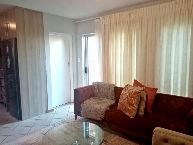 A living room area featuring tiled flooring, built-in cabinetry, and large windows with curtain treatments.