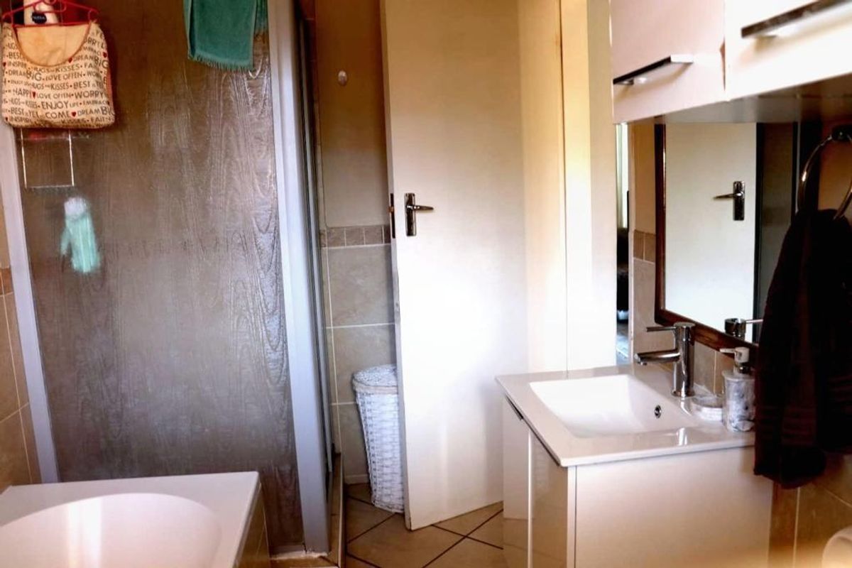 A functional bathroom featuring a vanity with a basin, a wall-mounted mirror, and a separate shower enclosure with tiled finishes.