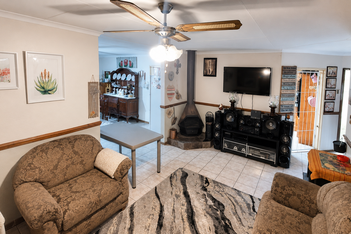 A spacious living room featuring tiled flooring, a central ceiling fan, and a freestanding fireplace, creating a comfortable and functional family living area.