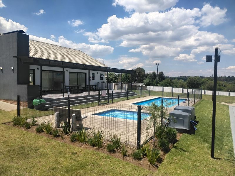 A well-maintained outdoor pool area featuring a paved patio, perimeter fencing, and direct access to the main residence via sliding glass doors.