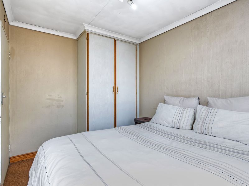 A bedroom featuring a built-in wardrobe, coving, and skirting boards, requiring cosmetic updates to the wall and ceiling finishes.