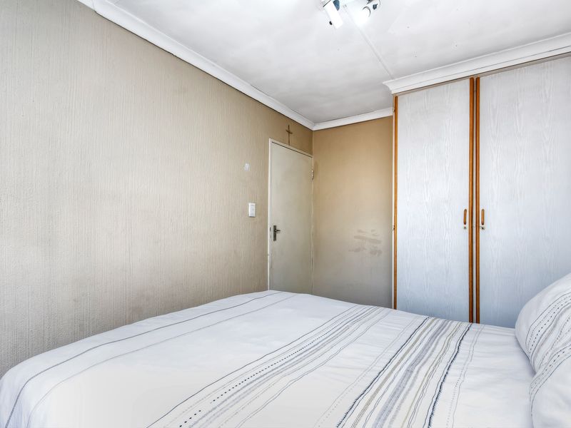 A bedroom featuring built-in cupboards and coving, showing signs of wear on the walls and ceiling that would benefit from cosmetic updates.