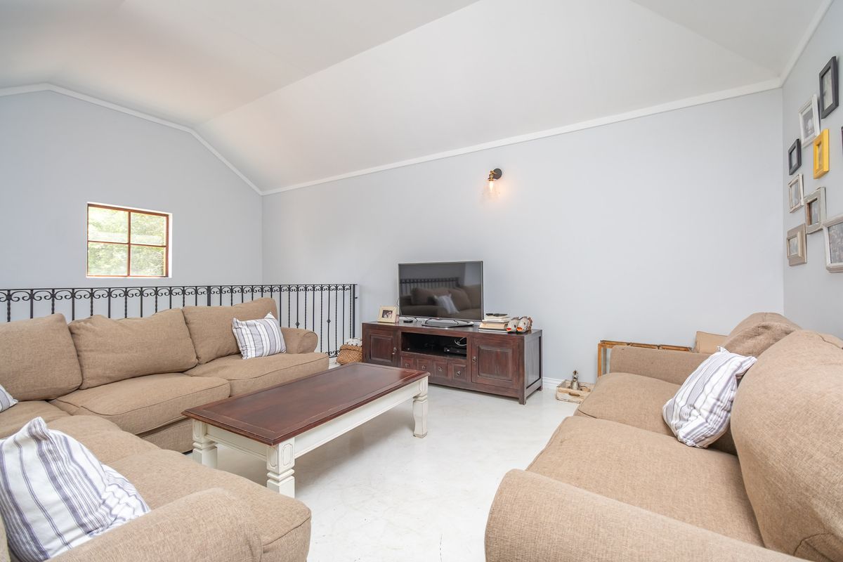 A bright living room featuring a high vaulted ceiling, a decorative wrought iron balustrade, and a wall-mounted light fixture.