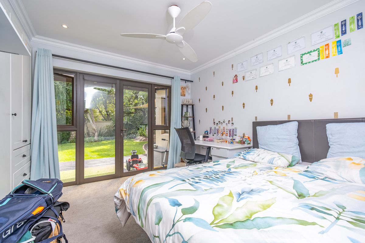A bright bedroom featuring a ceiling fan, built-in wardrobe, and sliding glass doors providing direct access to the rear garden.