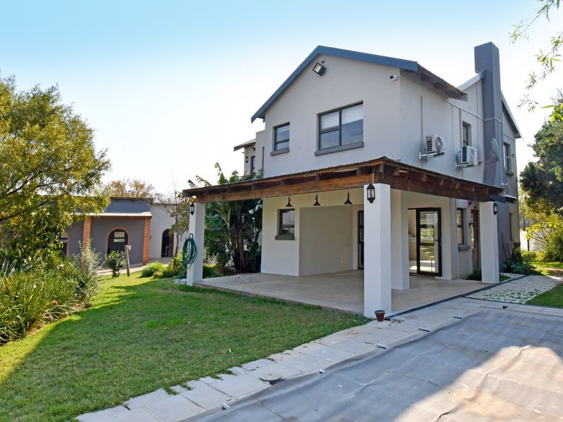 Rear view of the property featuring a covered patio with a timber pergola, landscaped garden, and external air conditioning units.