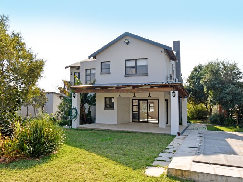 Rear view of a two-story house featuring a covered patio, a swimming pool with a cover, and a landscaped garden area.