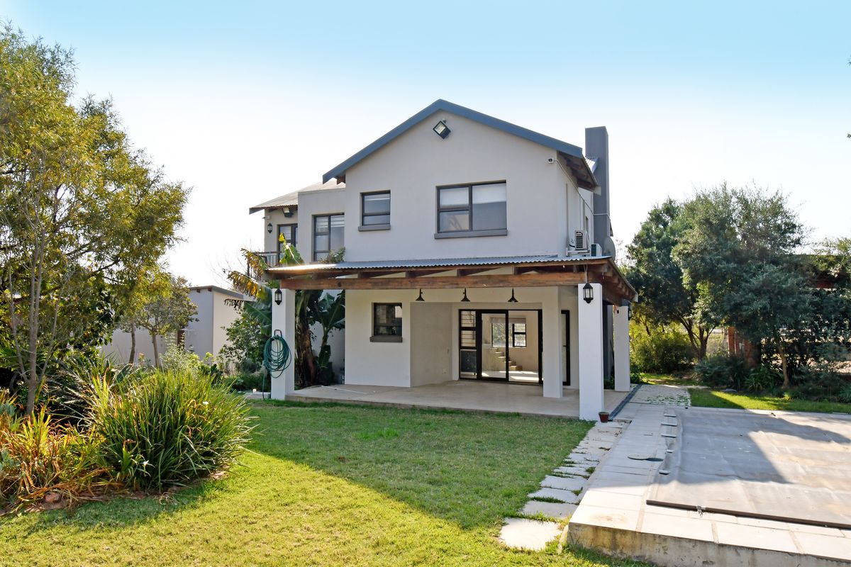 Rear view of a two-story house featuring a covered patio, a swimming pool with a cover, and a landscaped garden area.