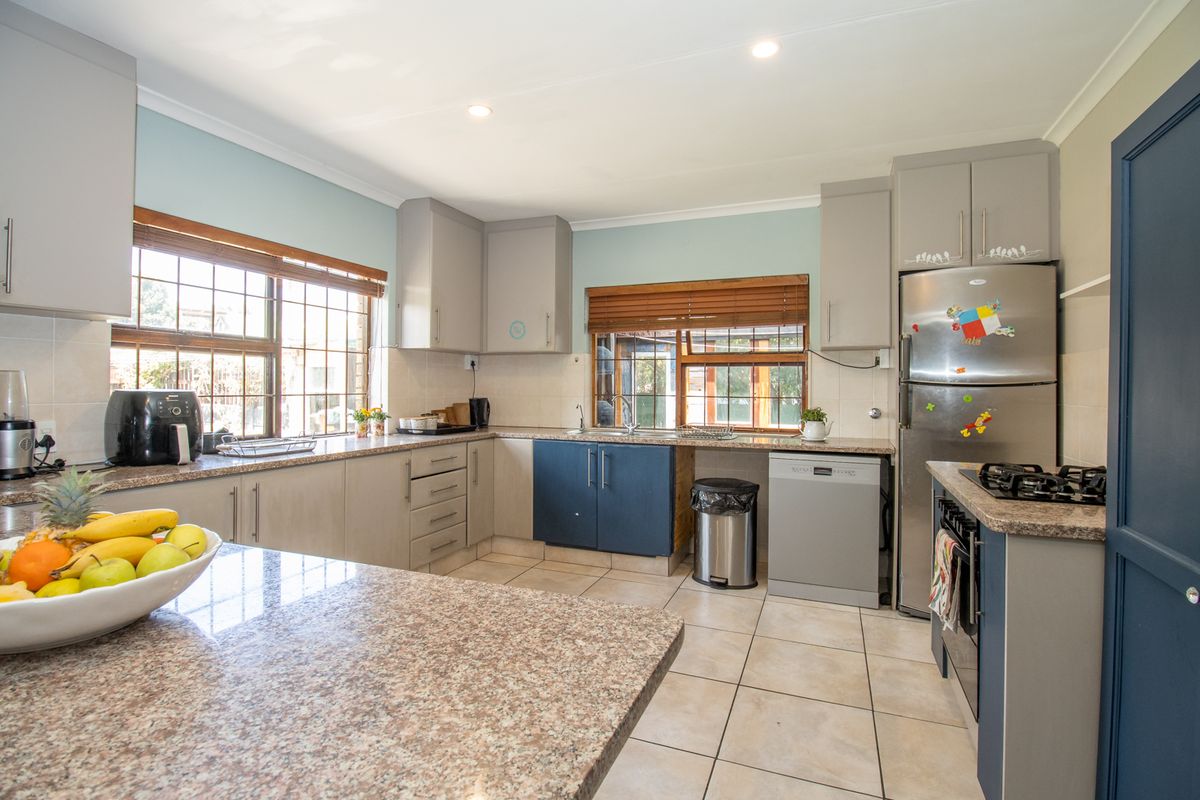 A functional kitchen featuring granite countertops, ample built-in cabinetry, a gas hob, and tiled flooring, offering a practical layout for daily cooking.