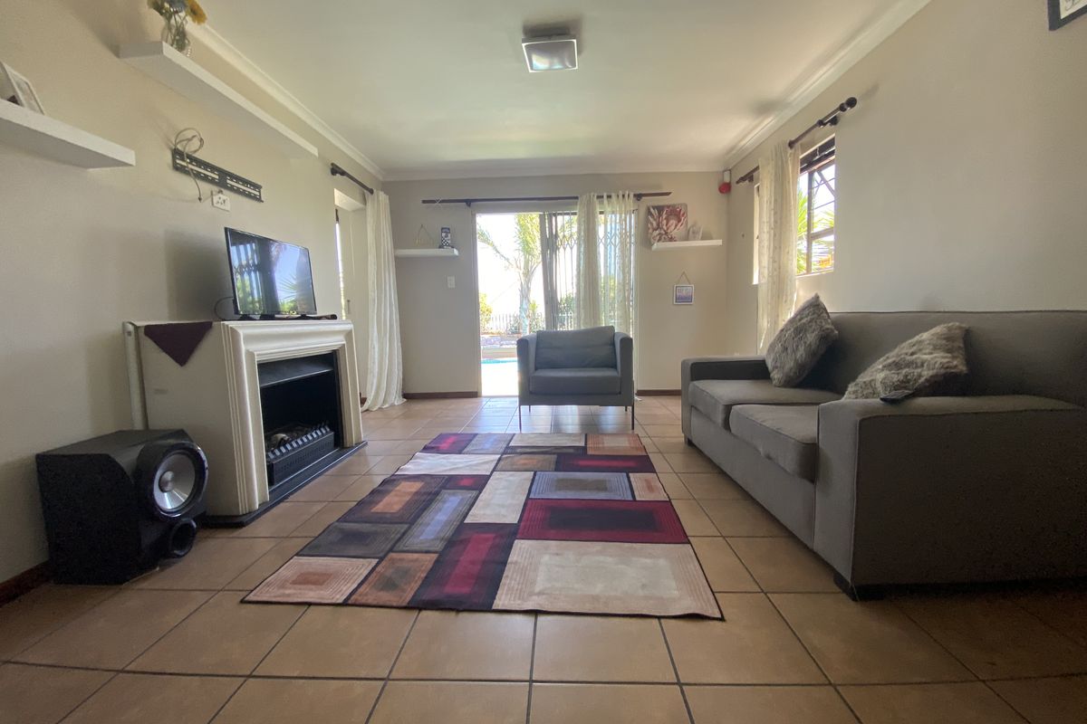 A living room featuring tiled flooring, a built-in fireplace, and a sliding glass door providing access to the outdoor area.