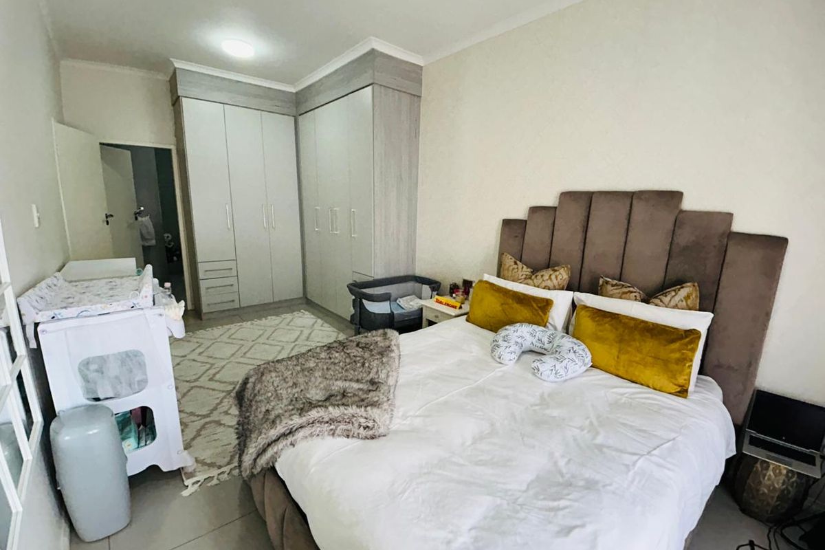 A well-maintained bedroom featuring neutral tiled flooring, modern built-in cupboards, and a spacious layout suitable for a comfortable sleeping area.