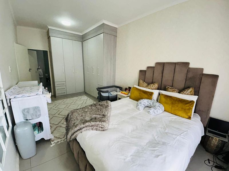 A well-maintained bedroom featuring neutral tiled flooring, modern built-in cupboards, and a spacious layout suitable for a comfortable sleeping area.