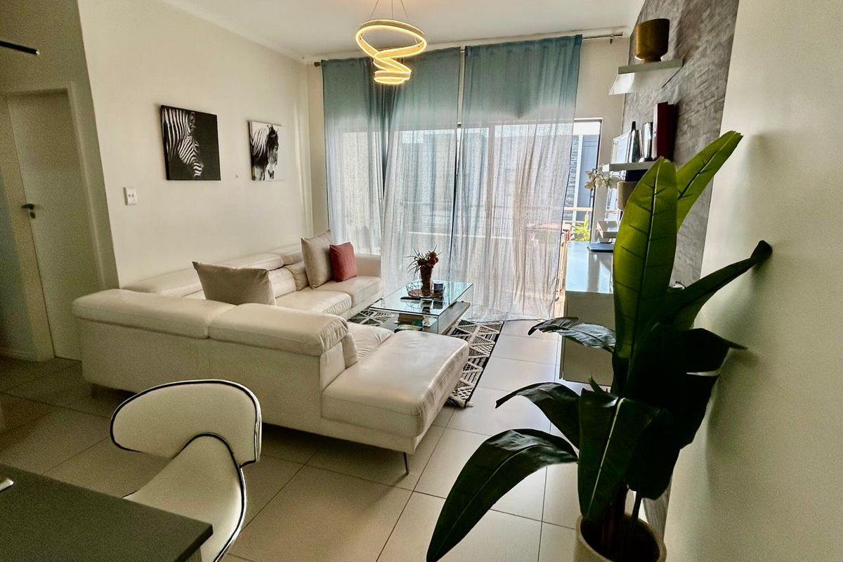 A bright and modern living room featuring tiled flooring, a textured feature wall, and a large sliding glass door leading to an outdoor area.