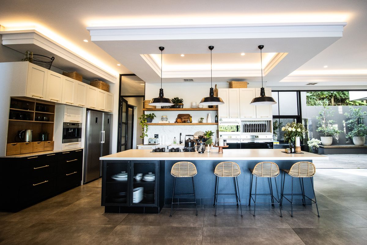 Modern open-plan kitchen featuring a large central island, high-end built-in appliances, custom cabinetry, and sophisticated recessed and pendant lighting.