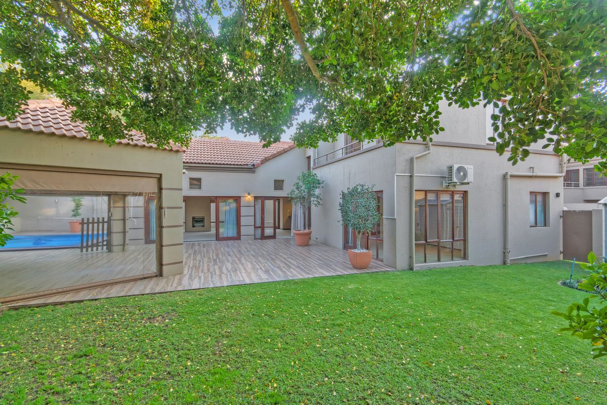 A spacious rear garden featuring a tiled patio area, a swimming pool, and well-maintained lawn, providing an ideal space for outdoor living and entertainment.