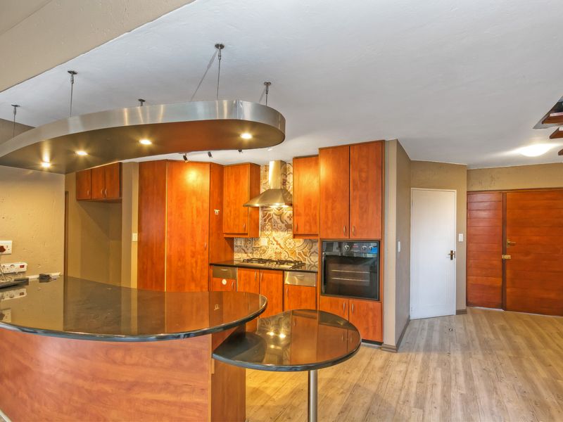 Kitchen featuring wood-finish cabinetry, granite countertops, built-in oven, gas hob, and a unique suspended bulkhead with integrated lighting.