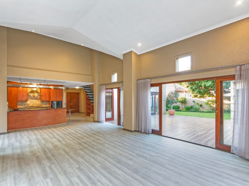 Spacious open-plan living area featuring vaulted ceilings, a functional kitchen with timber cabinetry, and large sliding doors opening onto a rear patio and garden.