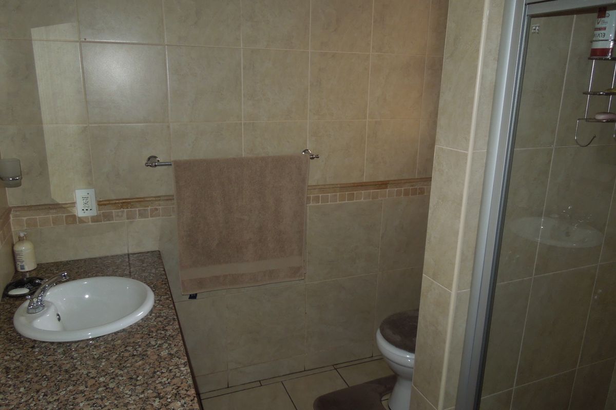 A functional bathroom featuring a granite vanity countertop, undermount sink, ceramic tiling, and a separate shower enclosure.