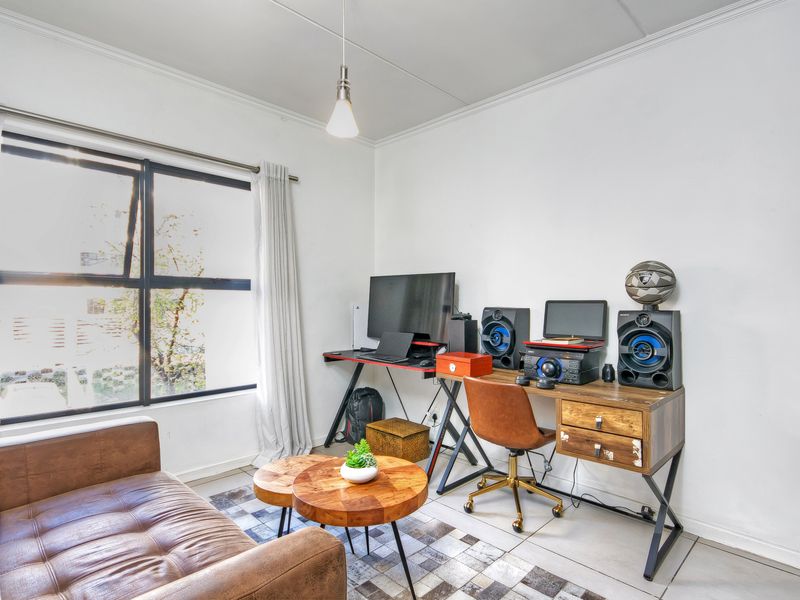 A bright living room featuring tiled flooring, a large window providing natural light, and a coved ceiling with a modern pendant light fixture.