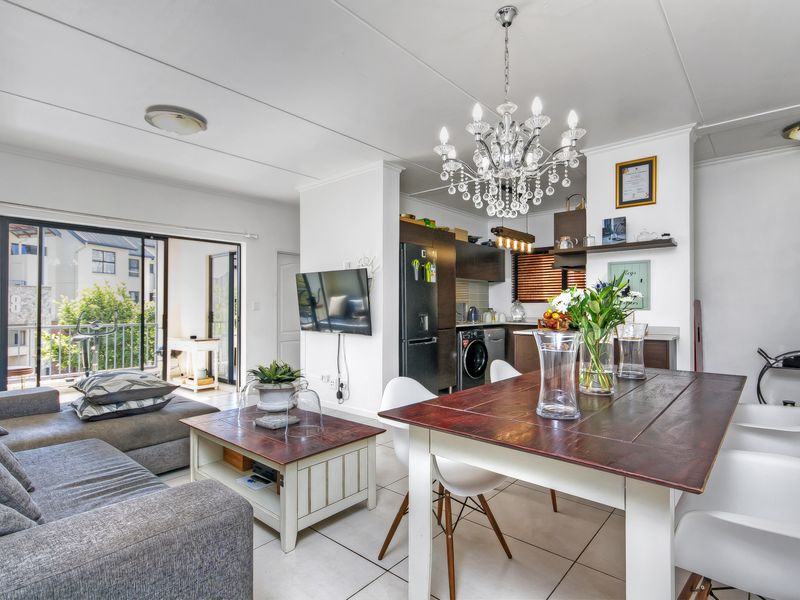 Open-plan living and dining area featuring tiled floors, a modern kitchen, and seamless access to a private balcony through sliding glass doors.