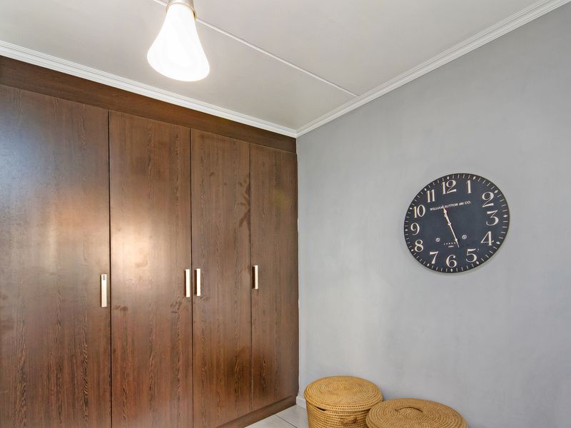 A bedroom featuring dark wood built-in cupboards, crown molding, and neutral grey wall finishes.