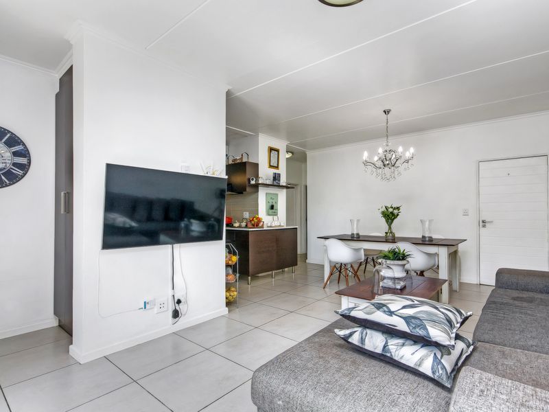 Open-plan living and dining area featuring neutral tiled flooring, a modern kitchen layout, and direct access to the rest of the apartment.