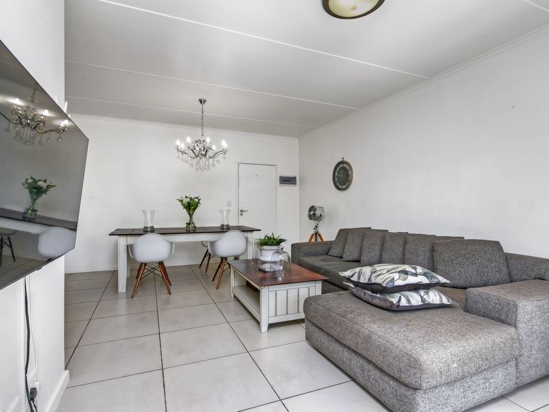 Open-plan living and dining area featuring neutral tiled flooring and a clean, minimalist aesthetic suitable for various interior design styles.
